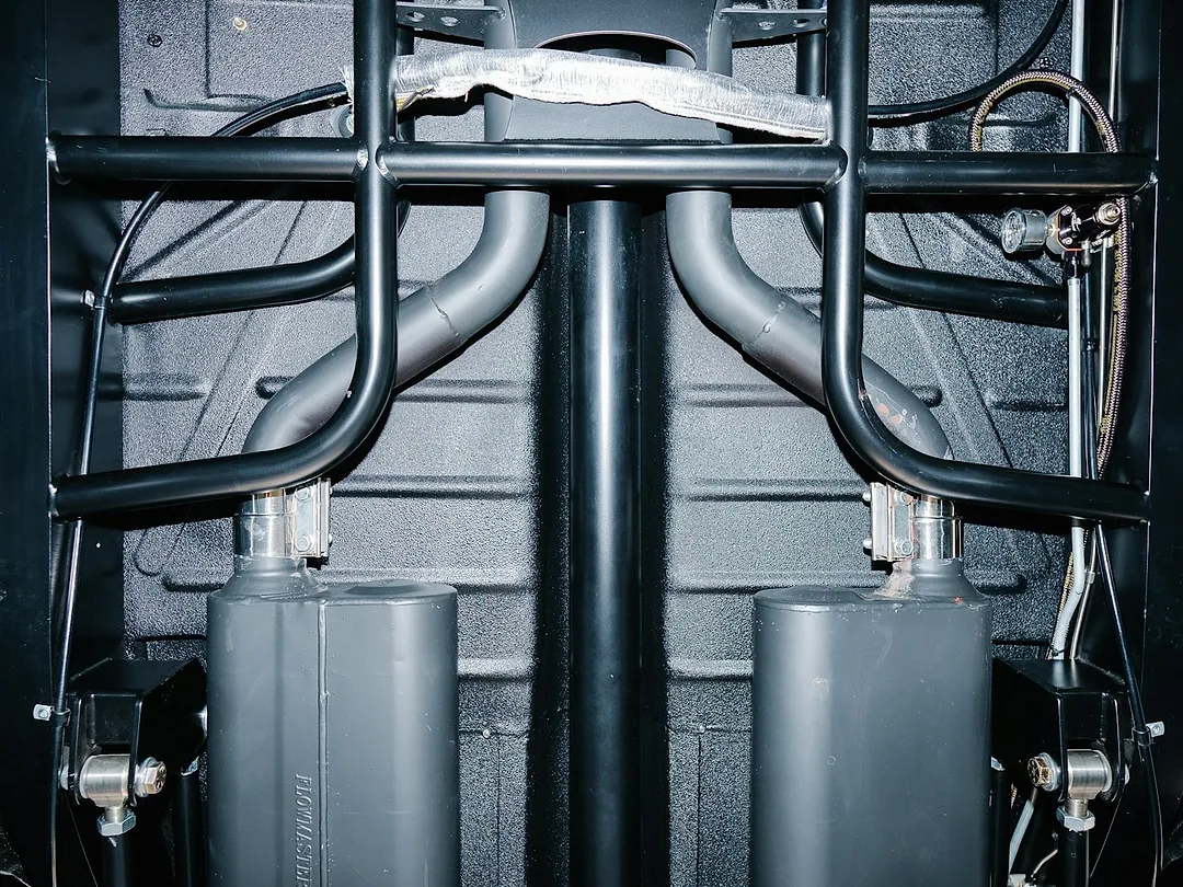 The underside of a car on a lift: floor pan, frame and exhaust